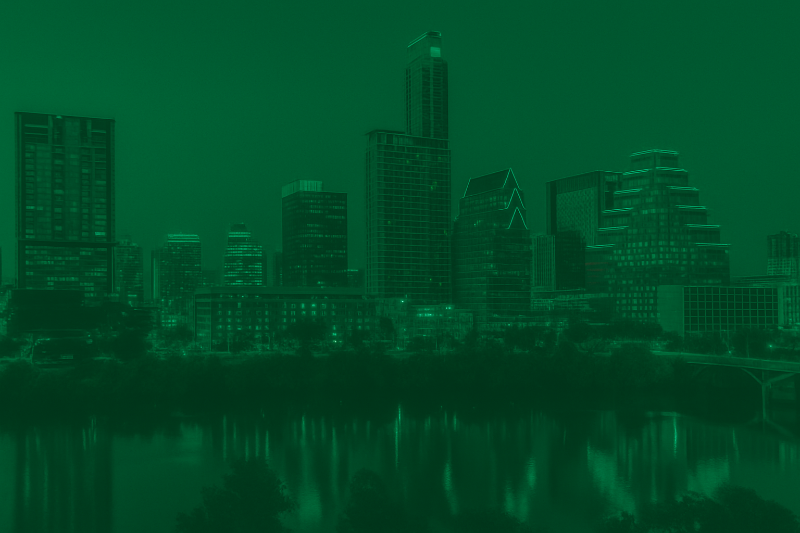 City skyline at night with reflections on water, green tint